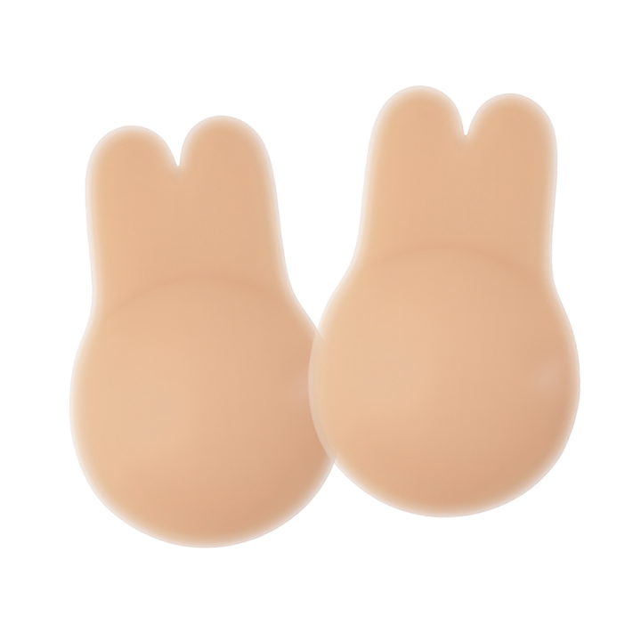 Pair of nude-colored Boob Bunnies breast lift pads with a bunny-ear shaped top and rounded base, made from smooth silicone material. Displayed on a transparent background with a subtle shine highlighting their soft, skin-like texture.